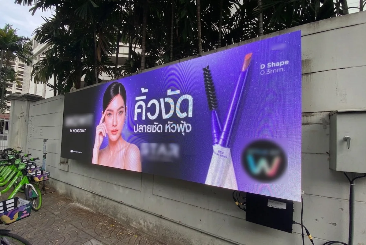 Outdoor-LED-Screen mit Werbemotiv an einer Mauer neben einem Gehweg